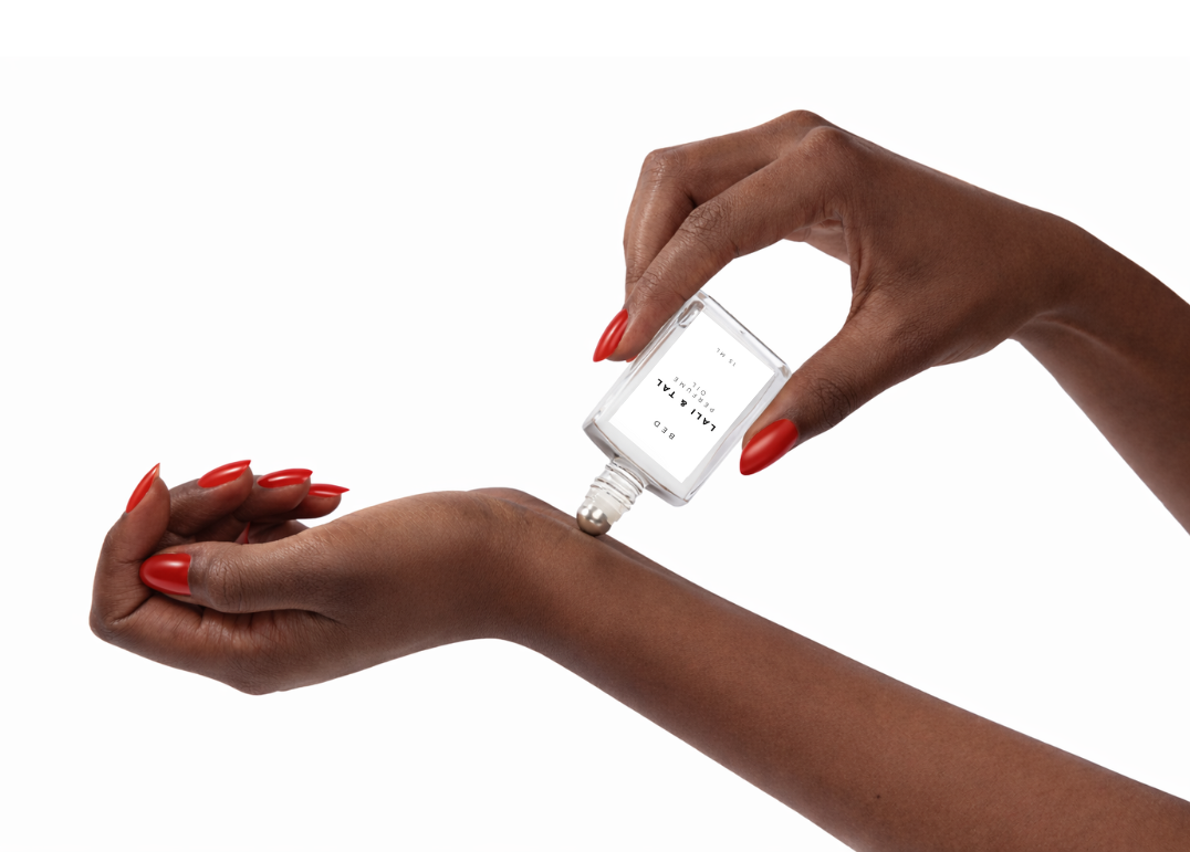 LALI & TAL BED perfume oil being applied to the wrist using a roll-on bottle.