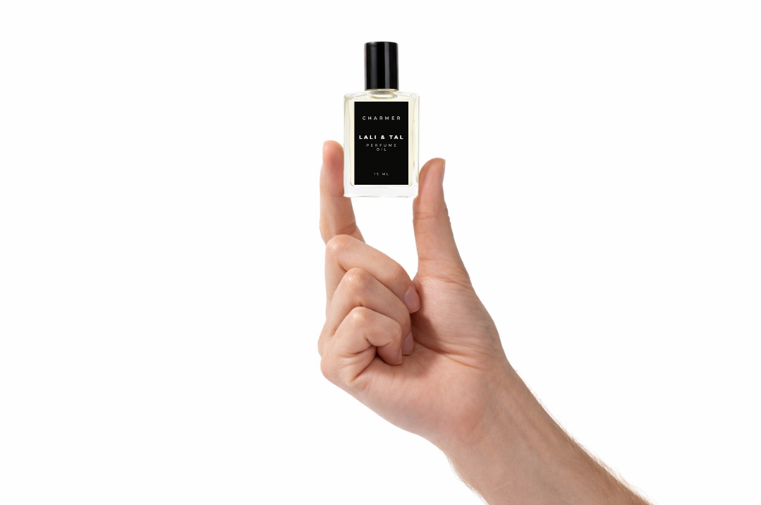 Hand holding a bottle of LALI & TAL CHARMER perfume oil to show size and scale.