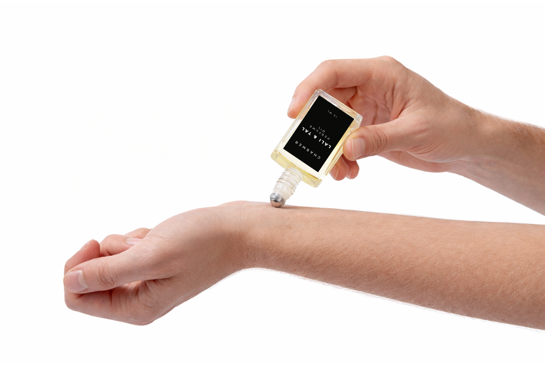 LALI & TAL CHARMER perfume oil being applied to the wrist using a roll-on bottle.