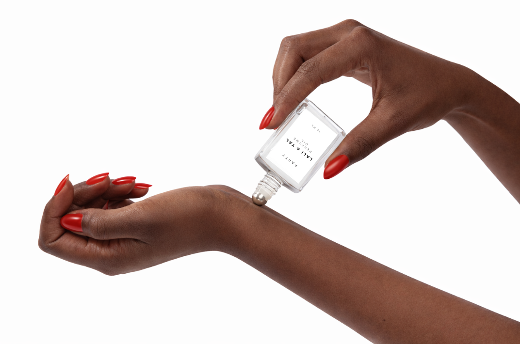 LALI & TAL PARTY perfume oil being applied to the wrist using a roll-on bottle.