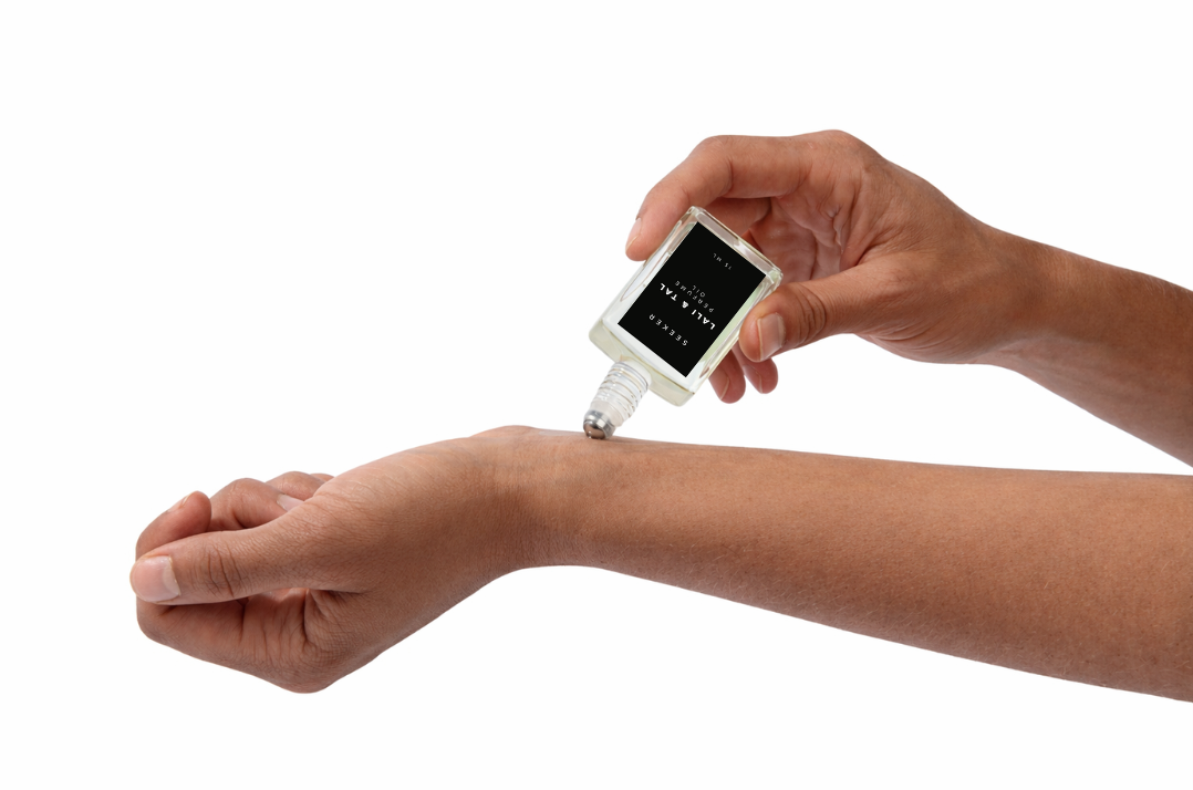 LALI & TAL SEEKER perfume oil being applied to the wrist using a roll-on bottle.