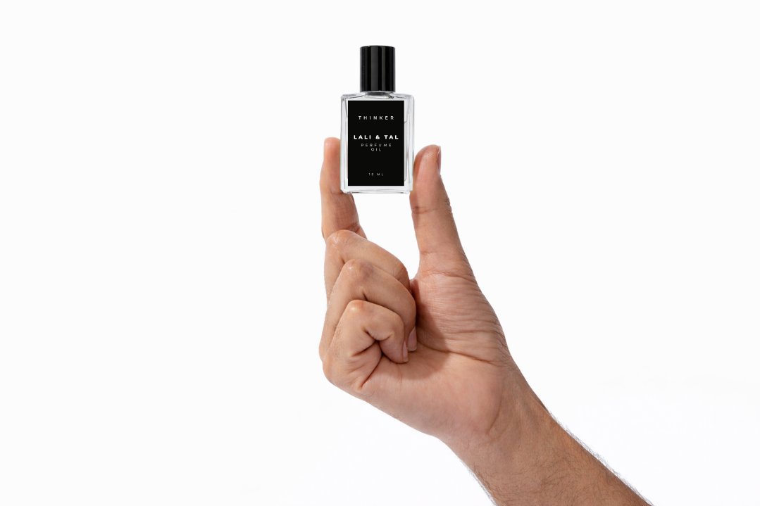 Hand holding a bottle of LALI & TAL THINKER perfume oil to show size and scale.