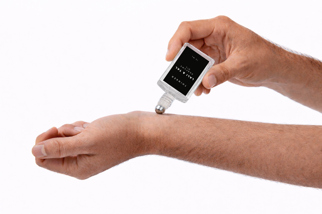 LALI & TAL THINKER perfume oil being applied to the wrist using a roll-on bottle.