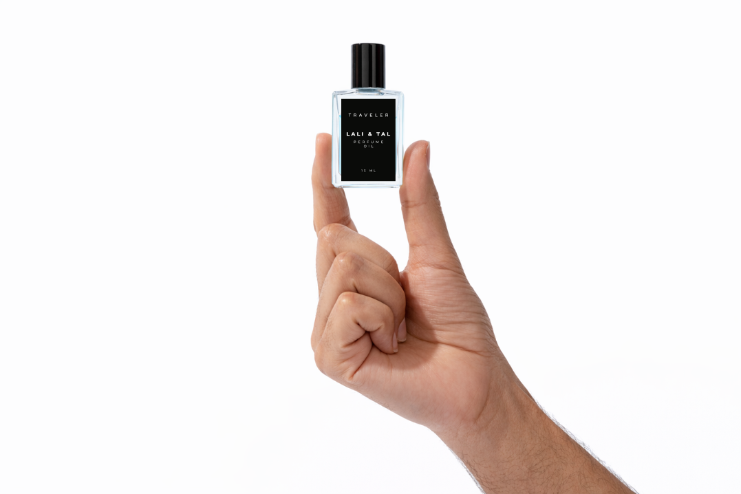Hand holding a bottle of LALI & TAL TRAVELER perfume oil to show size and scale.