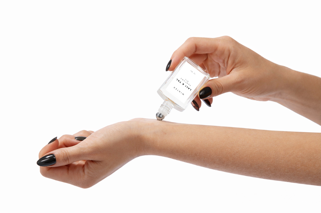 LALI & TAL WINTER perfume oil being applied to the wrist using a roll-on bottle.